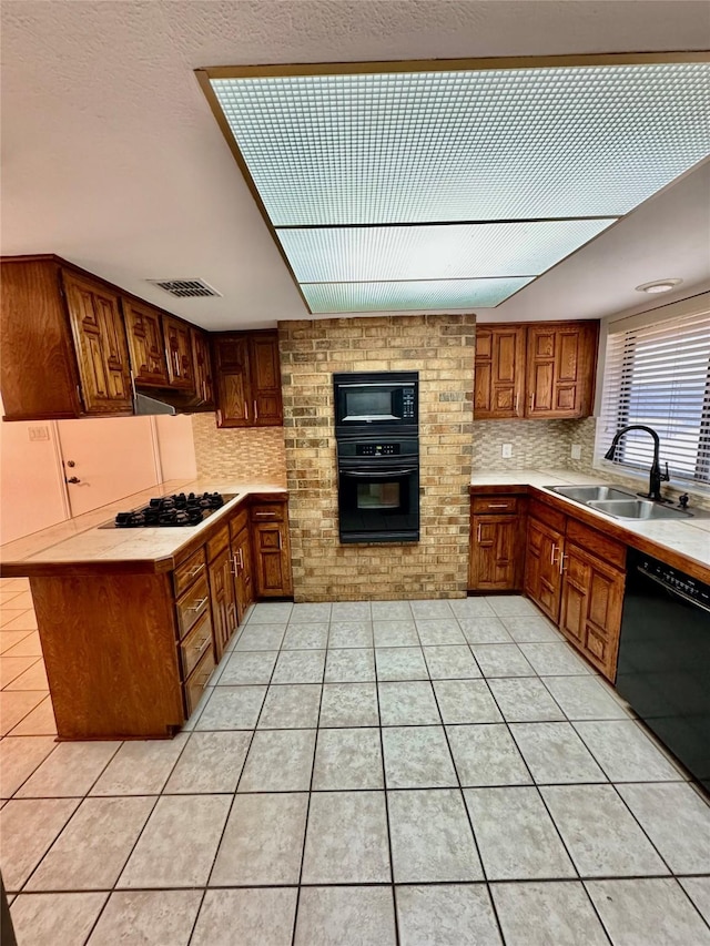 kitchen with backsplash, black appliances, sink, light tile patterned floors, and kitchen peninsula