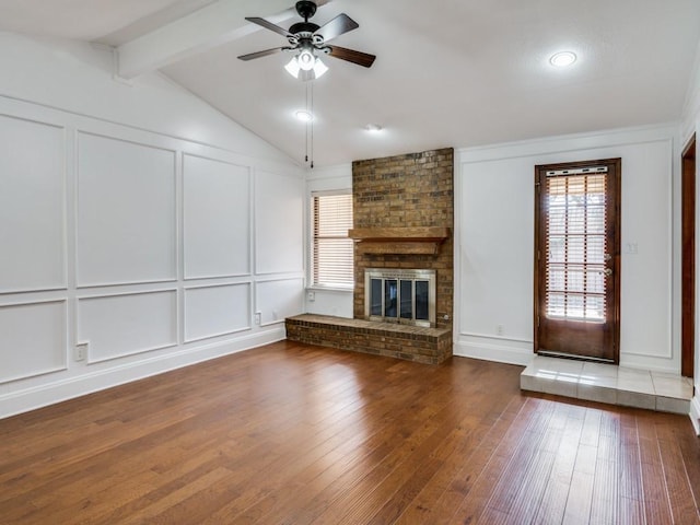 unfurnished living room featuring hardwood / wood-style flooring, ceiling fan, lofted ceiling with beams, and a brick fireplace