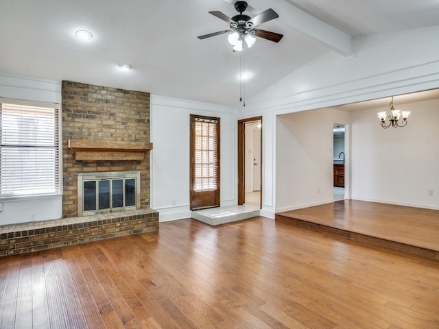 unfurnished living room featuring hardwood / wood-style floors, lofted ceiling with beams, a wealth of natural light, and a brick fireplace