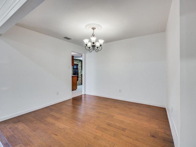 empty room featuring hardwood / wood-style floors and a chandelier