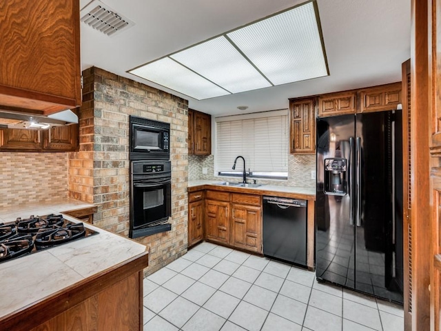 kitchen with black appliances, light tile patterned floors, sink, and tasteful backsplash