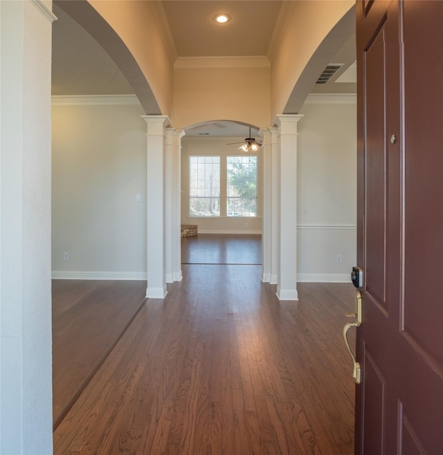 interior space featuring dark hardwood / wood-style floors, ceiling fan, ornate columns, and crown molding