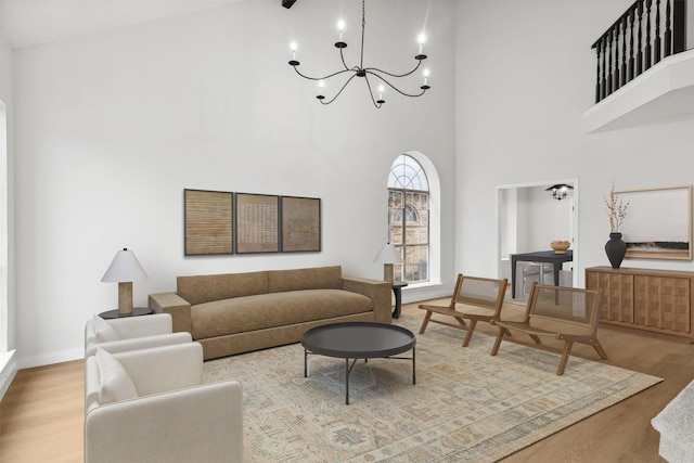 living room with a chandelier, a high ceiling, and light hardwood / wood-style flooring