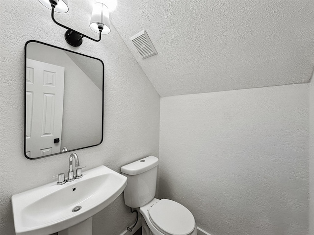 bathroom featuring sink, vaulted ceiling, and toilet