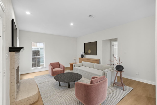 living room featuring a brick fireplace and light hardwood / wood-style flooring