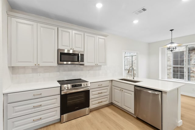 kitchen featuring kitchen peninsula, stainless steel appliances, light hardwood / wood-style flooring, and sink