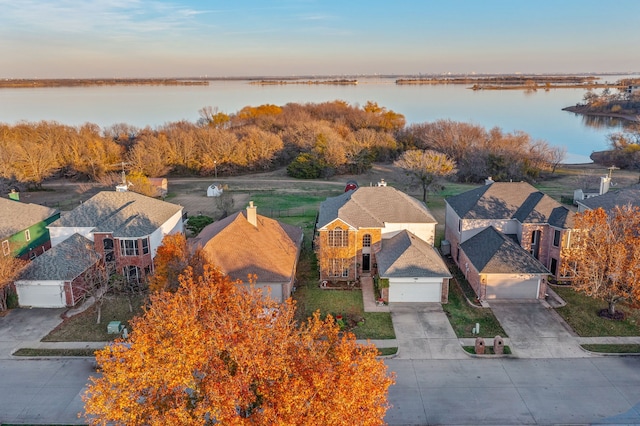 aerial view at dusk featuring a water view and a residential view