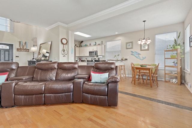 living room with crown molding, light hardwood / wood-style flooring, and a notable chandelier