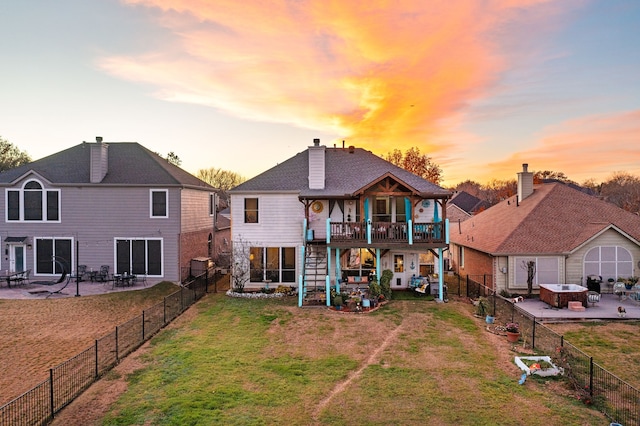 back house at dusk featuring a yard, a balcony, and a patio