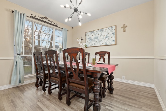 dining space with light hardwood / wood-style floors and an inviting chandelier