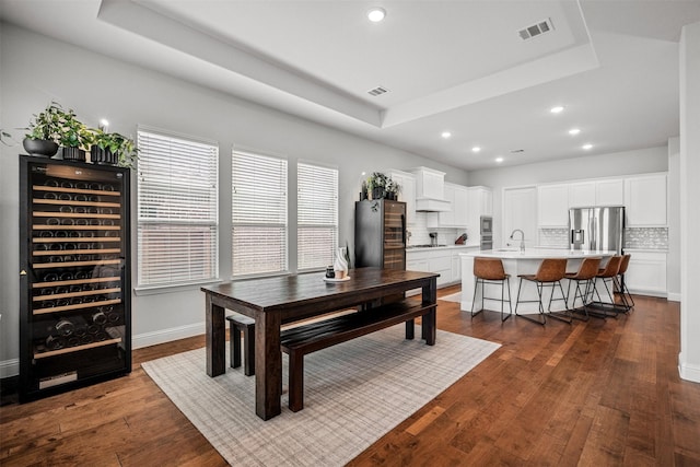 dining room featuring a tray ceiling, wine cooler, sink, and dark hardwood / wood-style floors