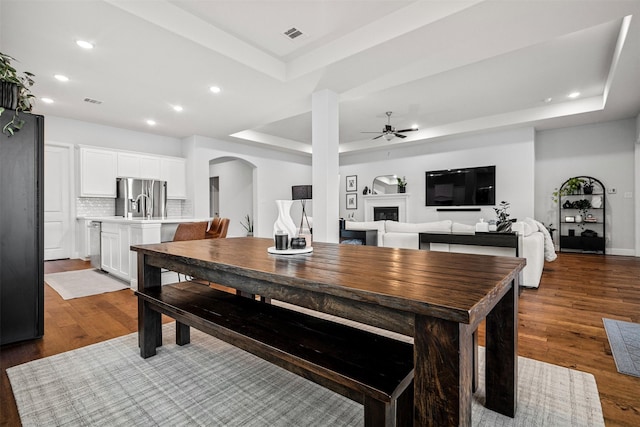 dining area with hardwood / wood-style floors, a tray ceiling, and ceiling fan