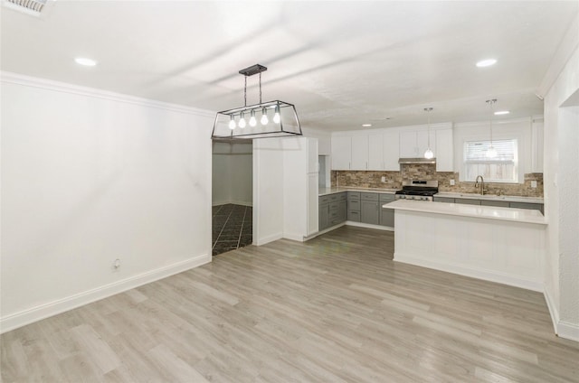 kitchen featuring sink, hanging light fixtures, backsplash, white cabinets, and stainless steel range oven