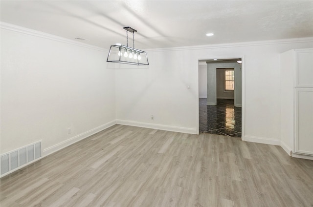 unfurnished dining area with ornamental molding, light wood-type flooring, visible vents, and baseboards