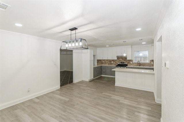 kitchen with sink, light hardwood / wood-style floors, white cabinets, stainless steel range oven, and decorative light fixtures