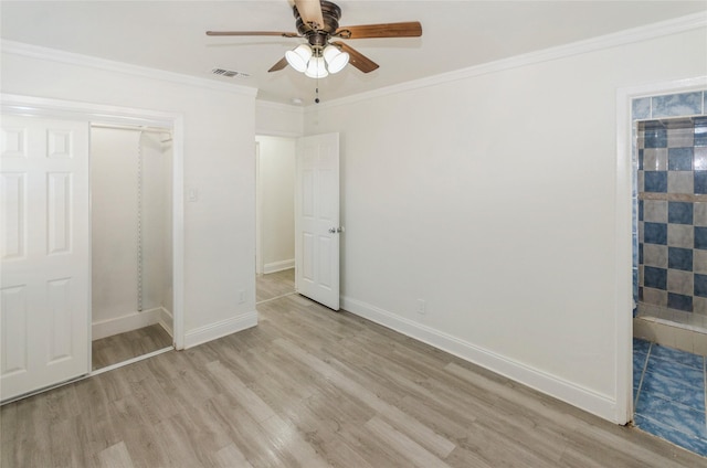 unfurnished bedroom featuring light wood finished floors, baseboards, visible vents, a ceiling fan, and crown molding