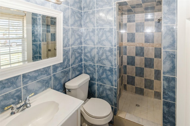 full bath with toilet, a stall shower, vanity, and tile walls