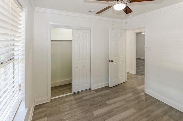 unfurnished bedroom with baseboards, visible vents, ornamental molding, wood finished floors, and a closet