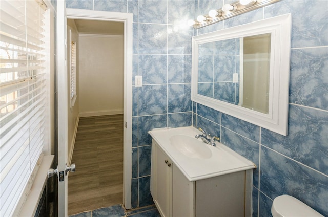 bathroom with hardwood / wood-style flooring, vanity, toilet, and tile walls