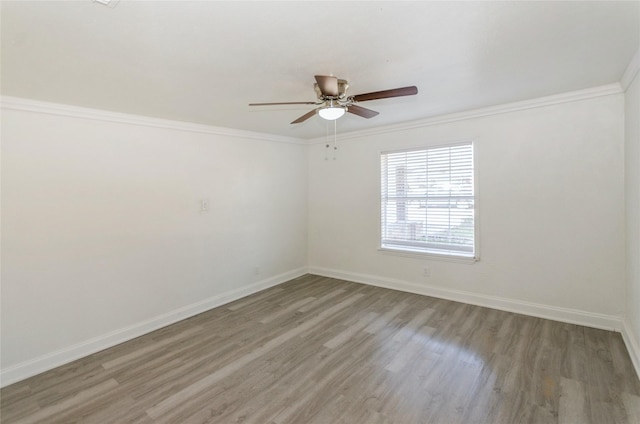 spare room with ornamental molding, a ceiling fan, baseboards, and wood finished floors