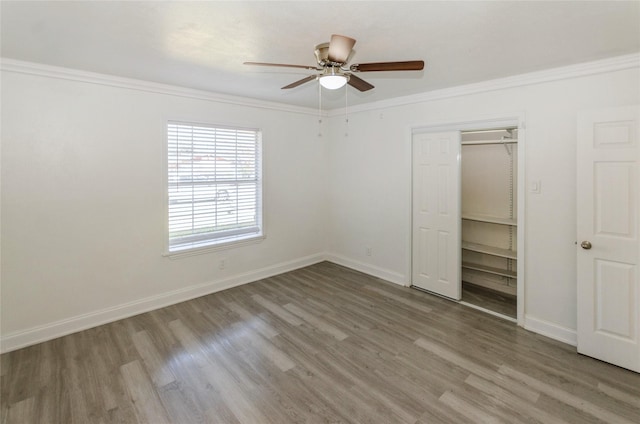 unfurnished bedroom featuring ornamental molding, a closet, ceiling fan, and light wood-type flooring