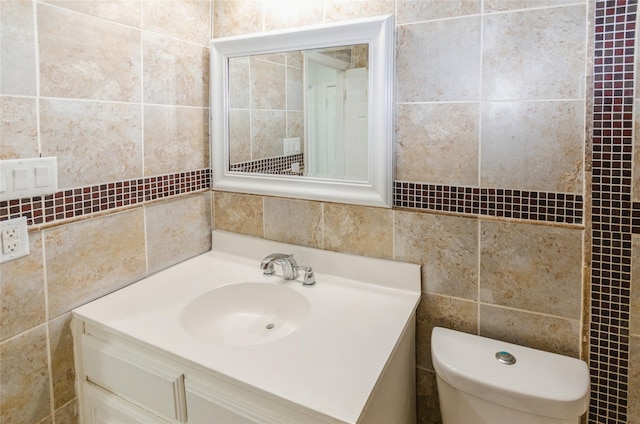 bathroom with tasteful backsplash, vanity, tile walls, and toilet