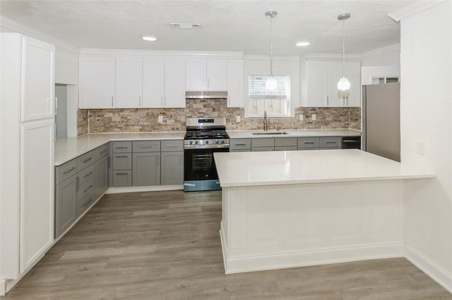 kitchen with sink, gray cabinetry, hanging light fixtures, stainless steel appliances, and ventilation hood