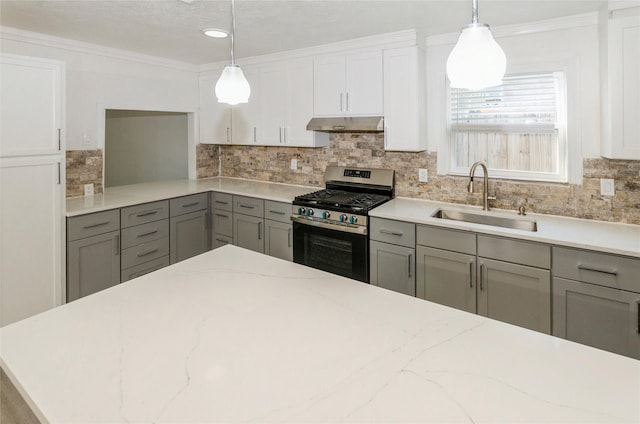 kitchen with under cabinet range hood, a sink, stainless steel gas range, gray cabinets, and tasteful backsplash