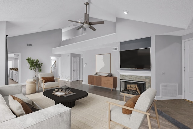 living room with hardwood / wood-style floors, ceiling fan, a textured ceiling, and high vaulted ceiling