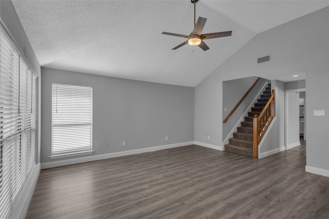 unfurnished living room with a textured ceiling, ceiling fan, dark wood-type flooring, and vaulted ceiling