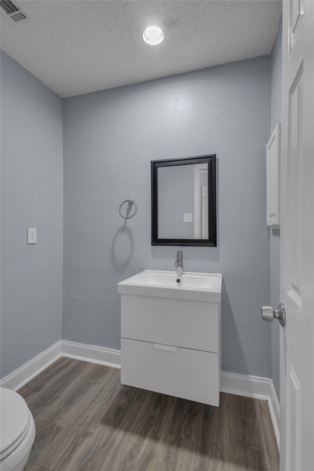 bathroom with wood-type flooring, a textured ceiling, and toilet