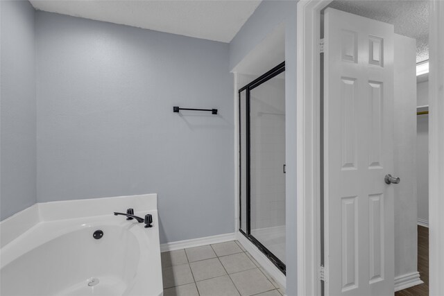 bathroom featuring shower with separate bathtub, a textured ceiling, and tile patterned floors