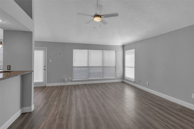 unfurnished living room featuring dark hardwood / wood-style floors, ceiling fan, and a textured ceiling