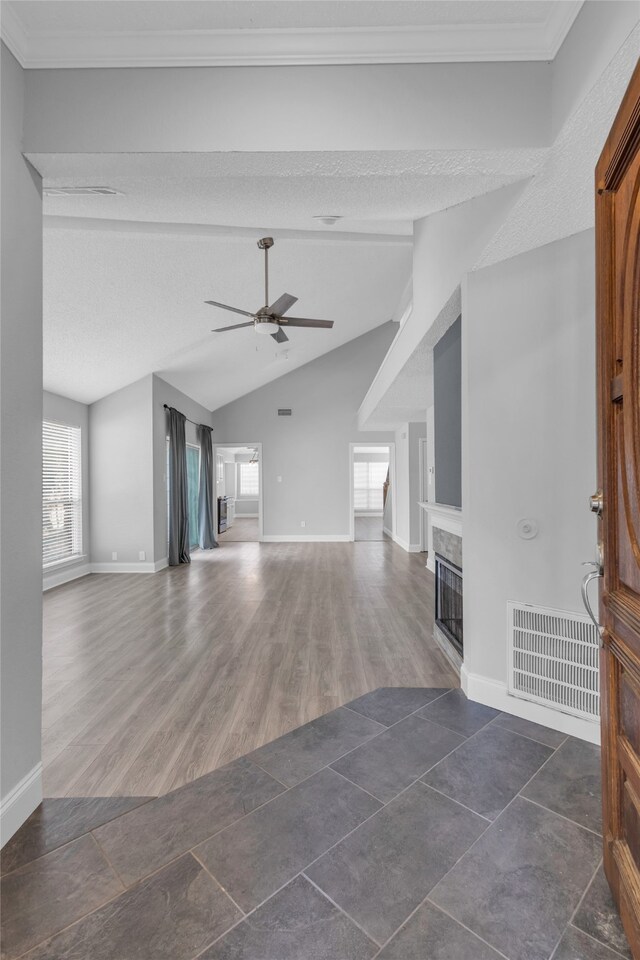 unfurnished living room with lofted ceiling, crown molding, dark hardwood / wood-style floors, ceiling fan, and a textured ceiling