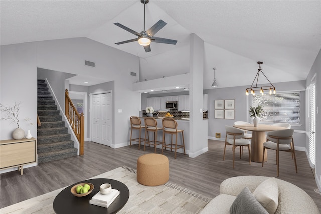 living room featuring hardwood / wood-style flooring, ceiling fan with notable chandelier, a textured ceiling, and high vaulted ceiling