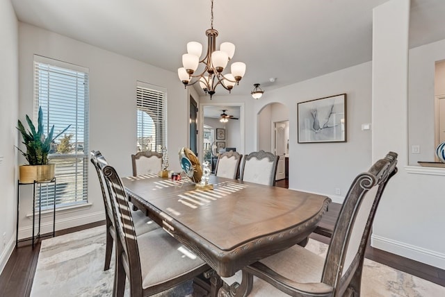 dining space with wood-type flooring and ceiling fan with notable chandelier