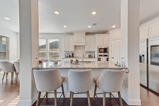 kitchen featuring sink, dark hardwood / wood-style flooring, decorative backsplash, stainless steel appliances, and light stone countertops