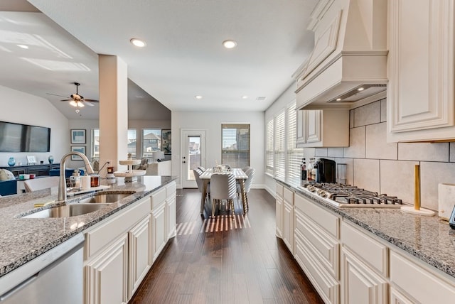 kitchen with premium range hood, sink, appliances with stainless steel finishes, light stone countertops, and white cabinets