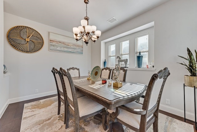 dining area with hardwood / wood-style floors and a notable chandelier