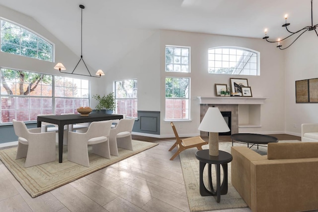 dining room featuring light hardwood / wood-style floors, a towering ceiling, a wealth of natural light, and an inviting chandelier