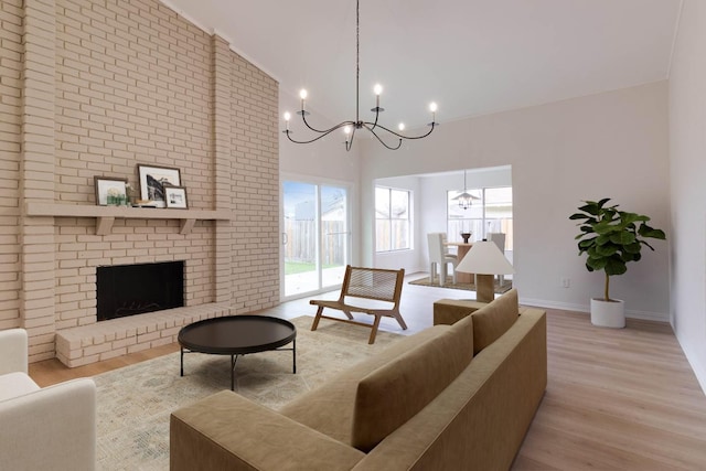 living room featuring a fireplace, a towering ceiling, light hardwood / wood-style floors, and a notable chandelier