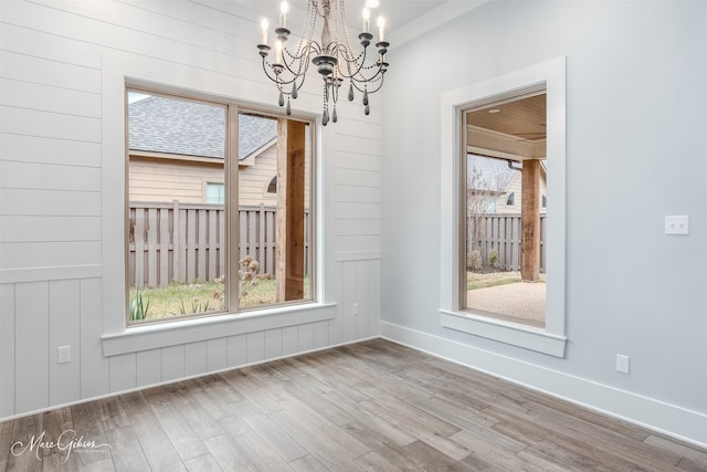 unfurnished dining area with hardwood / wood-style flooring and a chandelier