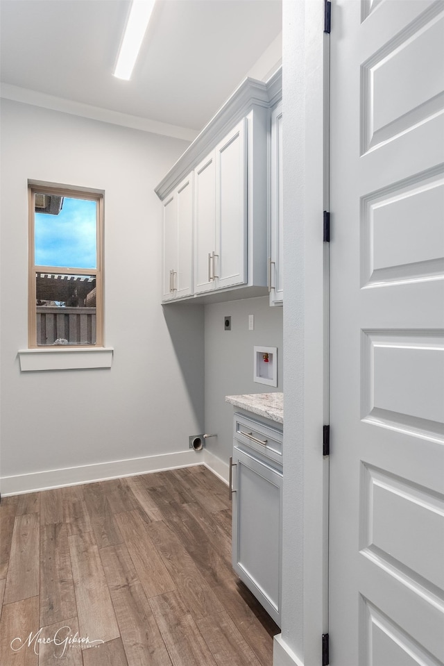 laundry room with dark wood-type flooring, crown molding, cabinets, electric dryer hookup, and washer hookup