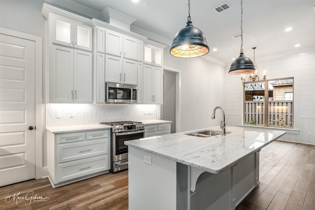 kitchen with appliances with stainless steel finishes, pendant lighting, white cabinetry, sink, and a kitchen island with sink