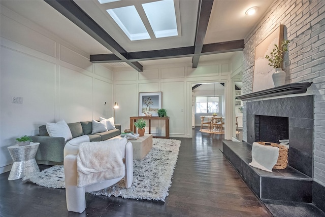 living room featuring dark hardwood / wood-style floors, a skylight, beam ceiling, and coffered ceiling