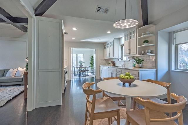 dining space featuring dark hardwood / wood-style flooring, beam ceiling, and sink