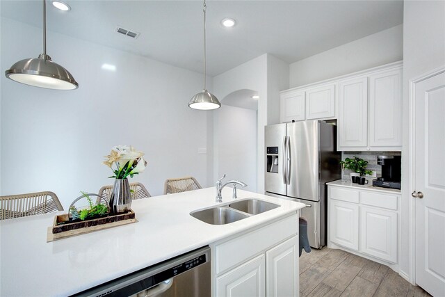 kitchen featuring white cabinets, sink, hanging light fixtures, light hardwood / wood-style flooring, and stainless steel fridge with ice dispenser