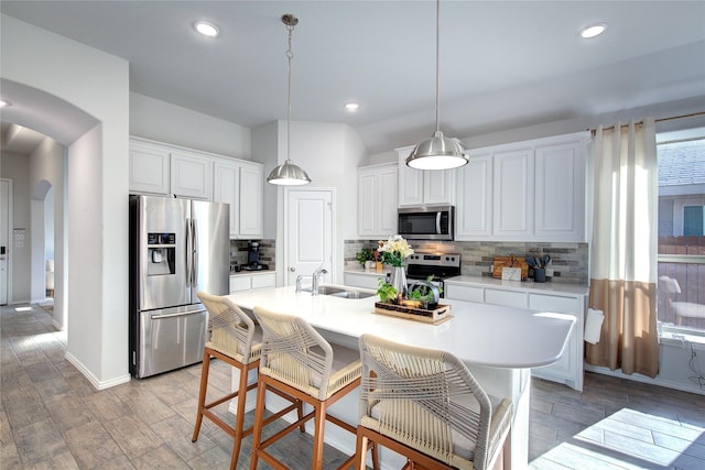 kitchen featuring stainless steel appliances, white cabinetry, light hardwood / wood-style floors, and an island with sink