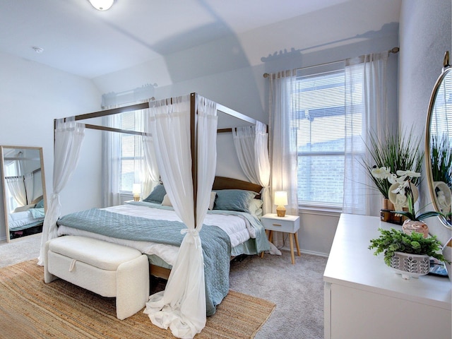 bedroom with light colored carpet, lofted ceiling, and multiple windows