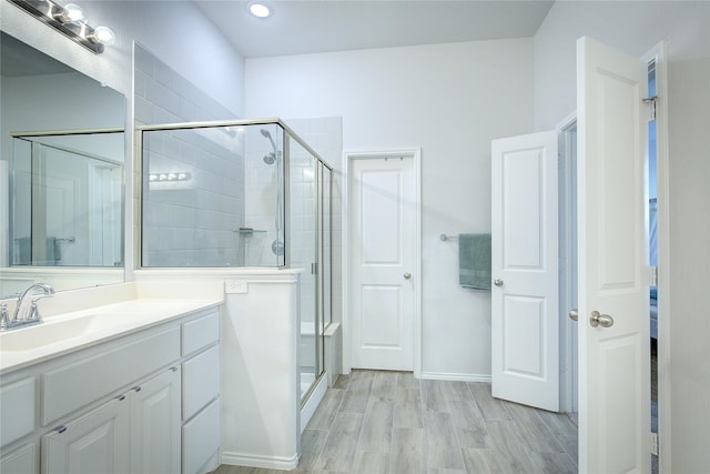 bathroom with hardwood / wood-style flooring, vanity, and a shower with door